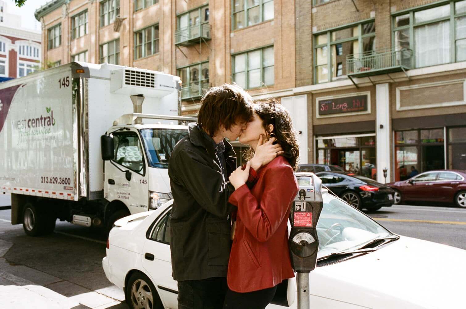 Парень и девушка целуются на улице с машинами