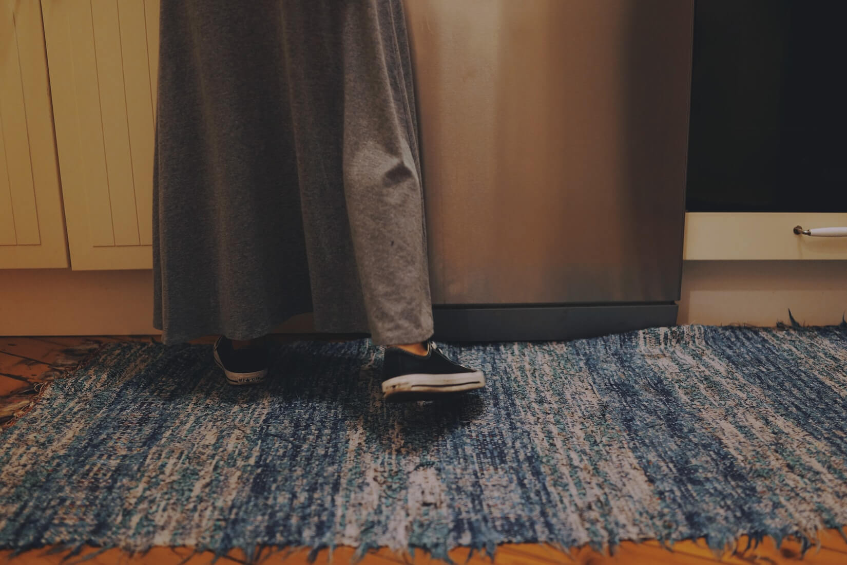 Девушка в юбке стоит на ковре, открывая шкаф
